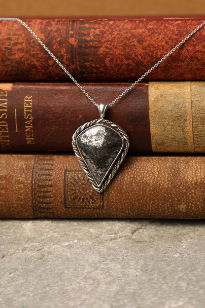 Silver pendant necklace on a stack of vintage books