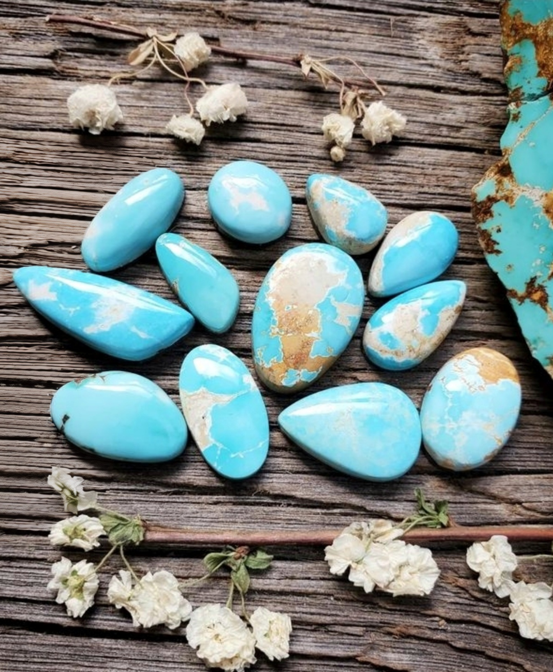 Turquoise stones on a wooden surface with white flowers